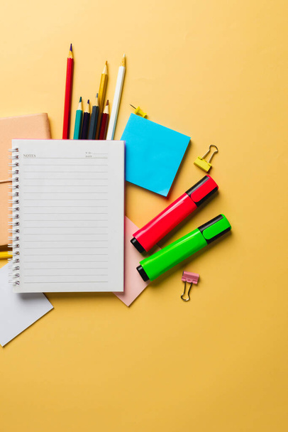 Vertical composition of notebook with copy space and school equipment on yellow surface. School equipment, tools and creativity concept. - Fotó, kép