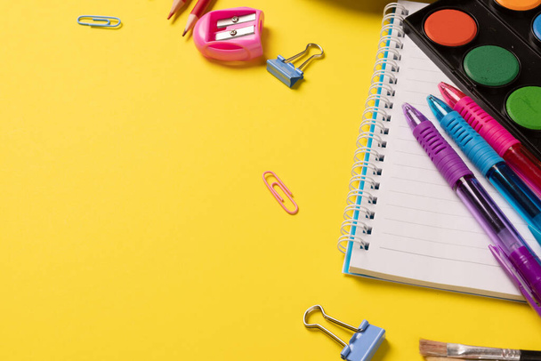 Imagine of various office supplies and plastic utensils, paints, crayons on yellow background. Education, learning and creativity. - Foto, imagen