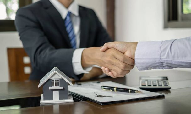 Empresarios y agentes de bienes raíces se dan la mano después de completar las negociaciones para comprar casas de seguros y firmar contratos. Concepto de seguro doméstico. - Foto, imagen