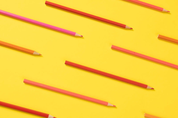 Imagine of crayons of different shades of pink on yellow background. Education, learning and creativity. - 写真・画像
