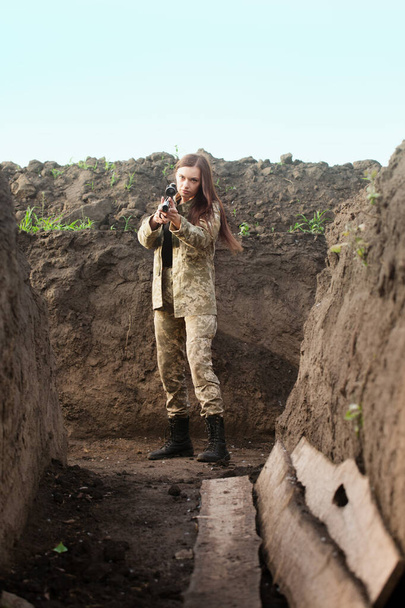 A beautiful girl with a weapon in her hands in the trench - Fotoğraf, Görsel