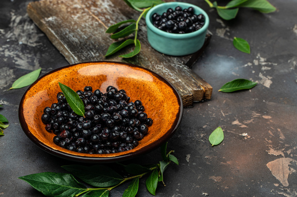 Superfoods antioxidant of indian mapuche. Bowl of fresh maqui berry on dark background, top view. - 写真・画像