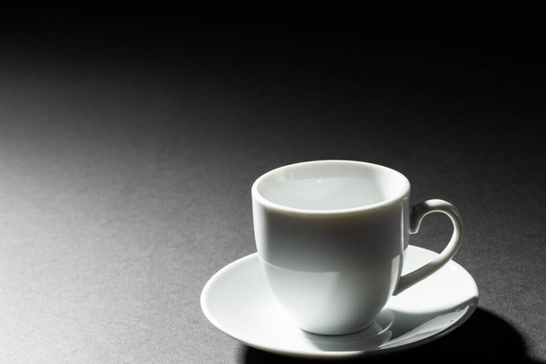 Image of empty white coffee cup and plate on black background. Coffee, refreshment and beverages. - Zdjęcie, obraz