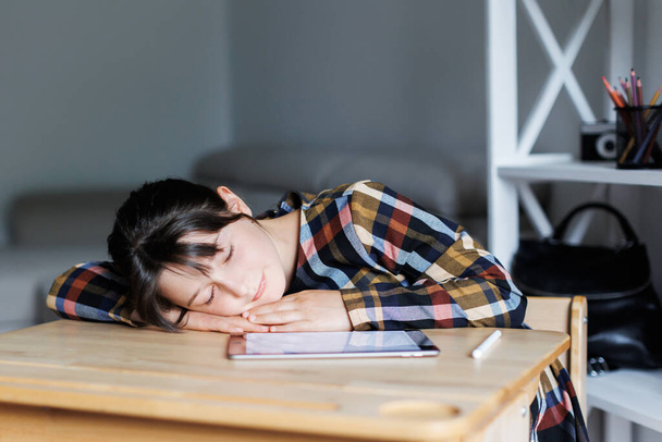 Moe en verveeld tienerschoolmeisje. Schoolmeisje slaapt terwijl het doen van huiswerk, moe van het studeren, uitgeput. - Foto, afbeelding