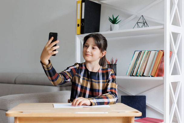 Happy teen girl holding modern cellphone gadget and taking photo herself. Girl using smartphone have webcam virtual event. Children technology concept. - Foto, Imagem