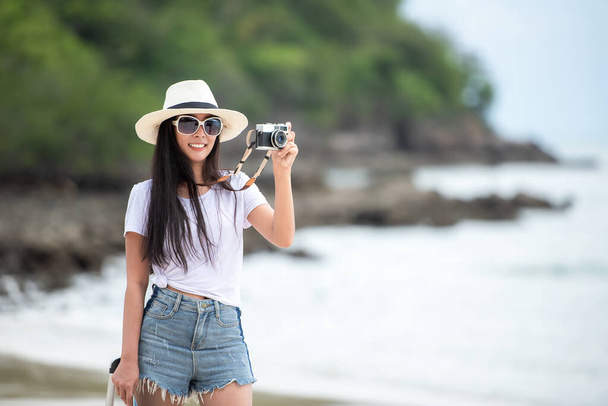 Happy traveler and tourism young women travel summer on the beach. Asian  people holding map and camera take photo  and relax outdoor for destination and leisure trip travel in holiday - 写真・画像