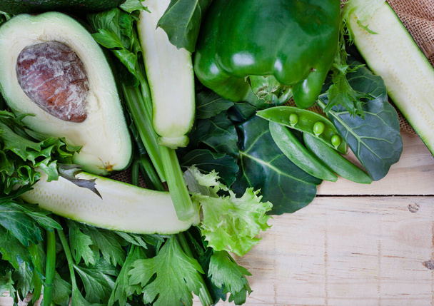 grünes Gemüse, Spinat, Avocado, Sellerie auf rohem Holz mit Kopierraum - Foto, Bild