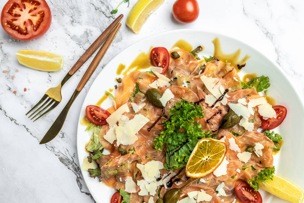 Salmon carpaccio with with capers, parmesan and cherry tomatoes. Delicious balanced food concept. - Φωτογραφία, εικόνα