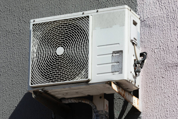建物の外にぶら下がっている熱交換器が付いている屋外のエアコンの単位. - 写真・画像