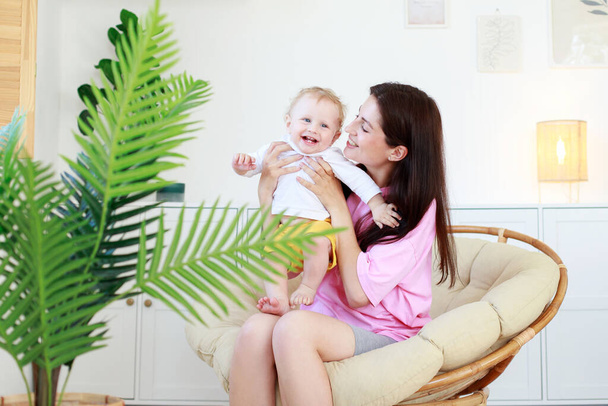 mom and baby are smiling in the living room at home. baby care. motherhood - Foto, Bild
