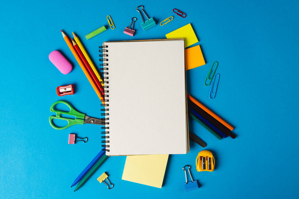 Composition of notebook with copy space and school tools on blue surface. School equipment, tools and creativity concept. - Фото, изображение
