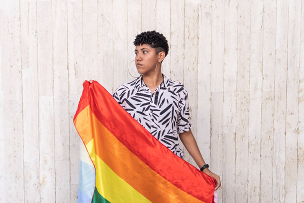 Созерцательная этническая женщина с флагом ЛГБТ на открытом воздухе - Фото, изображение