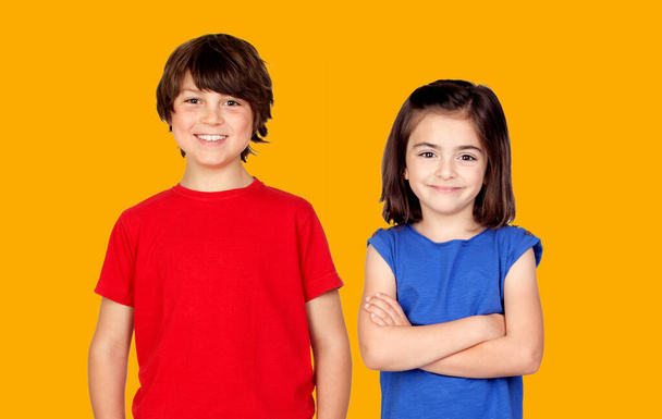Childhood, fashion and people concept - happy smiling boy and girl looking at camera isolated on a orange background - Photo, image