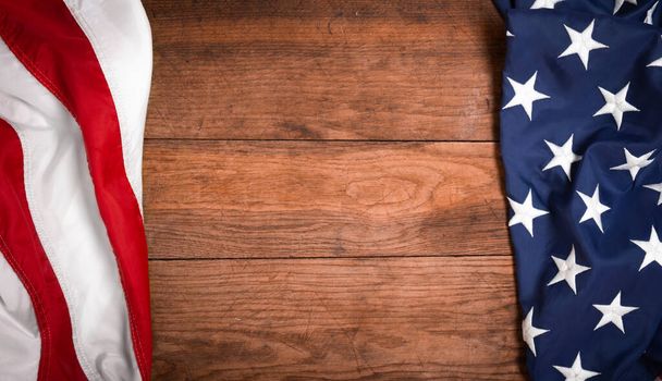 Flat lay USA flag on brown wooden board, vintage background with copy space top view. Banner, minimalism, loft style. American - 写真・画像