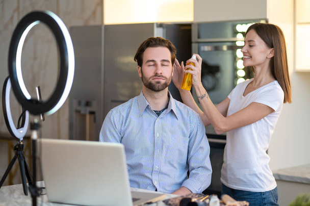 Appearance. Long-haired woman making hair to a man before webinar - Foto, Bild
