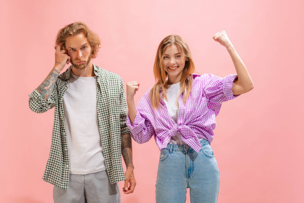 Portrait of young man and woman in casual clothes posing isolated over pink studio background. Happy and thoughtful look. Concept of youth, lifestyle, relationship, emotions, facial expression, ad - 写真・画像