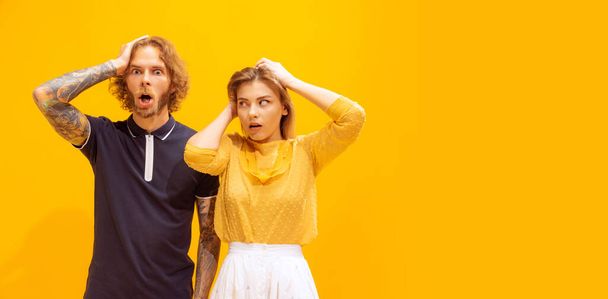 Portret van jonge man en vrouw in casual kleding poseren geïsoleerd over gele studio achtergrond. Schokkende uitdrukking. Concept van jeugd, levensstijl, relatie, emoties, gezichtsuitdrukking, reclame - Foto, afbeelding