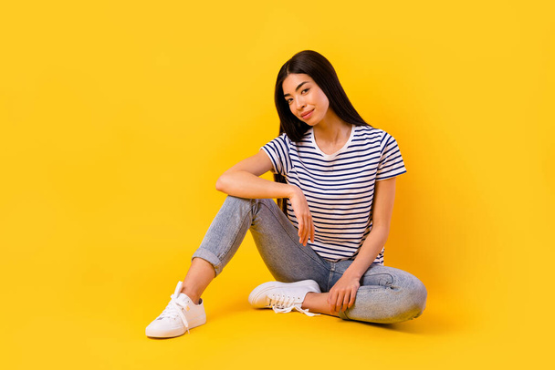 Full size portrait of pretty positive indonesian lady sit floor good mood isolated on yellow color background. - Foto, Bild
