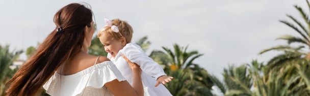 Rodzic bawiący się uśmiechniętym dzieckiem w letniej sukience w Walencji, sztandar  - Zdjęcie, obraz