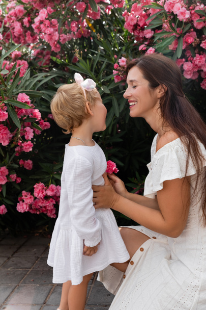 Hymyilevä nainen tilalla kukka ja koskettaa vauva tytär kesällä mekko Valencia - Valokuva, kuva