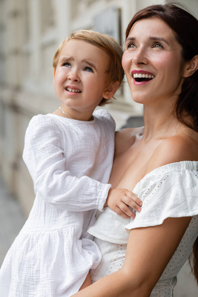 Portrait of excited mom holding focused baby girl outdoors in Valencia - Fotografie, Obrázek