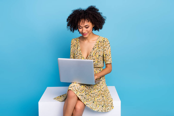 Foto di divertente affascinante donna indossare abito stampa seduta sedia piattaforma digitando gadget moderno isolato sfondo di colore blu. - Foto, immagini