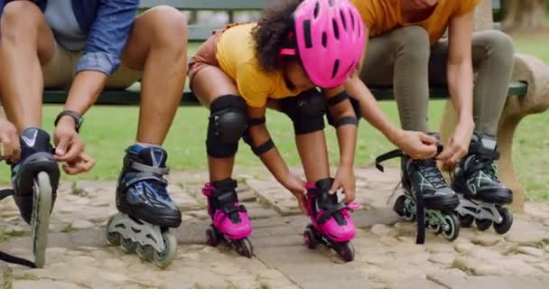 Close up on the feet of an active fun family in a park tying or putting on the rollerblade inline. A mother, father, and daughter preparing to skate, tying laces and straps while on a bench outdoors. - Footage, Video