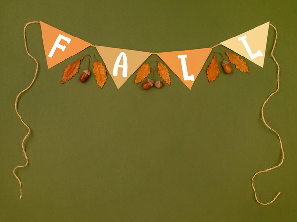 Fall lettering on cardboard. Top view of greeting paper garland with acorns and oak leaves on dark green background. Autumn theme border, frame. - Fotoğraf, Görsel
