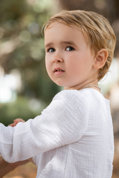 Portrait of toddler girl in shite dress looking away outdoors  - Foto, Imagen