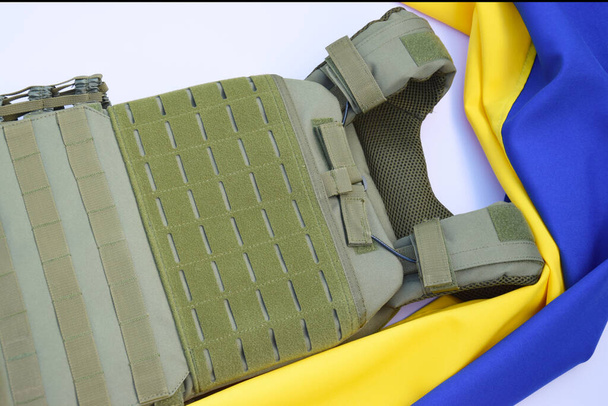 Tático, armadura corpo militar com placas no fundo da bandeira da Ucrânia. O conceito de proteger o corpo de tiros na guerra na Ucrânia. - Foto, Imagem