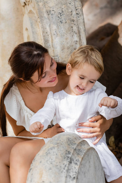 Весела мама обнімає дочку на кам "яній лавці у Валенсії.  - Фото, зображення