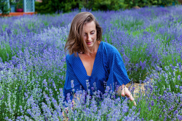 Girls in a blue dress are photographed in purple lavender flowers on a field - Photo, image