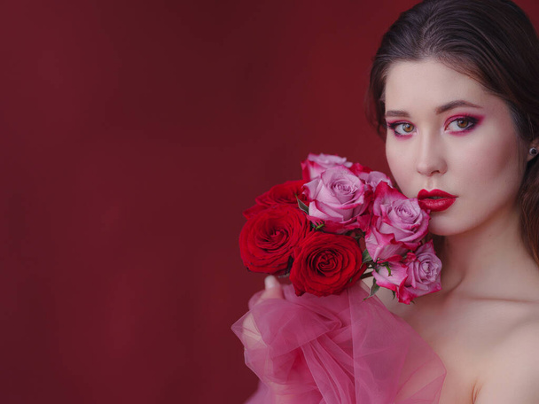 Привлекательная брюнетка азиатка с красивым букетом цветов. Красивая женщина с ярким макияжем. Арт-портрет с розами. Концепция ухода за кожей - Фото, изображение