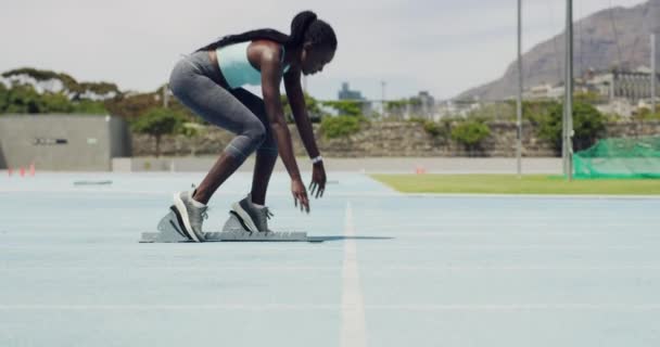 Runner in starting position with feet on angled pedals to begin a race on a sports track. Female athlete getting focused and ready to sprint in a lane while training to win an olympic competition. - Záběry, video