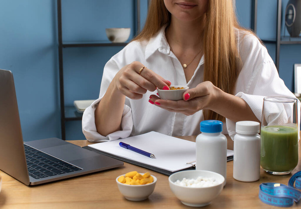 Nutritionist recommends omega3 supplement to client at video chat in office closeup. Woman holds bowl with gel capsules near laptop. Fatty acids - Foto, immagini