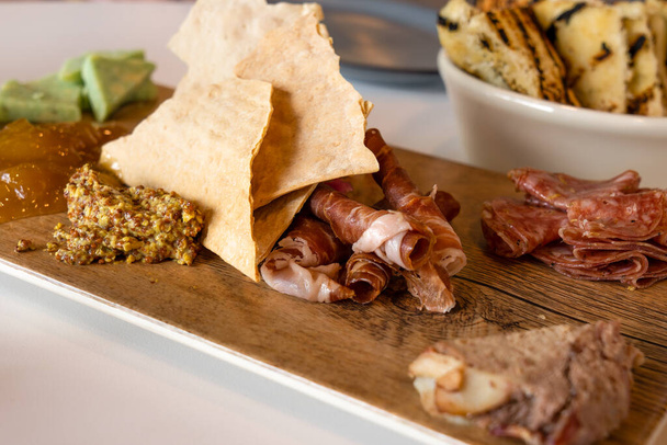 Charcuterie Board con enfoque selectivo contiene carnes, queso, chutney y mostaza - Foto, imagen