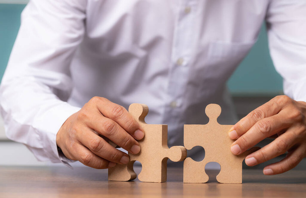 Businessman hand connecting jigsaw puzzle on desk, Business solutions, concept of success and strategy. - Photo, image