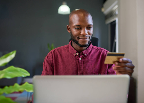 Um negro faz compras on-line a partir de sua mesa de escritório com cartão de crédito. Foto de alta qualidade - Foto, Imagem