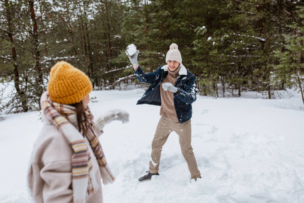 people, season and leisure concept - happy couple playing snowballs in winter park - Photo, Image
