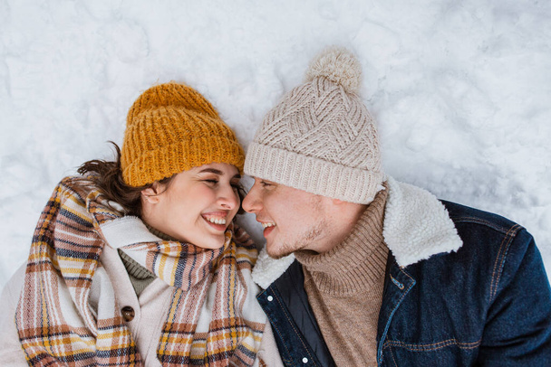 people, love and leisure concept - happy smiling couple lying on snow in winter - 写真・画像