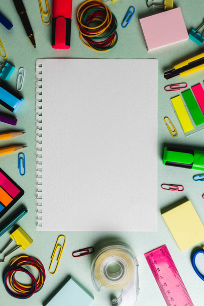Vertical composition of notebook with copy space and frame made of school tools on green surface. School equipment, tools and creativity concept. - Valokuva, kuva