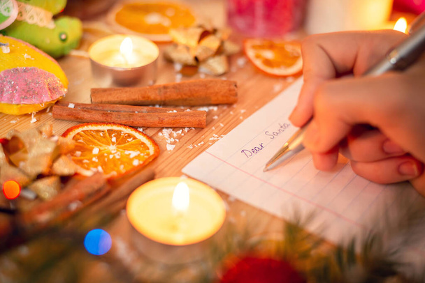 Před Vánocemi se splní přání. Dítě píše Santovi dopis, ve kterém popisuje všechny sny a žádá o dárky; slavnostní pozadí. - Fotografie, Obrázek