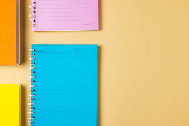 Composition of colorful notebooks lying on yellow surface with copy space. School equipment, tools and creativity concept. - Photo, Image