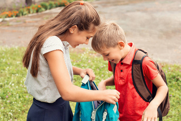 Two school learners siblings happily looking into the backpack, playing and having marry time together - 写真・画像