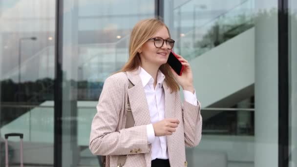 A successful businesswoman talking on her cell phone in the city center. Business woman walking down the street, talking on her cell phone. A serious professional woman talking on the phone. . High - Footage, Video
