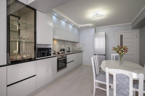 Interior de la moderna cocina blanca de moda bien diseñada con mesa de comedor, vista a la esquina - Foto, Imagen