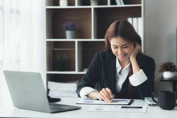Business woman working in a private office, she is reviewing the company's financial documents sent from the finance department before he takes it to a meeting with a business partner. Financial concept. - Foto, Imagen