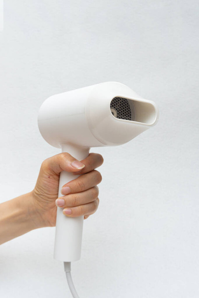 A woman drying her hair with a hair dryer - Foto, afbeelding