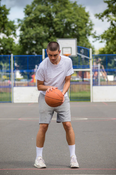 A Nineteen Year Old Teenage Boy Playing Basketball in A Public Park - Foto, imagen