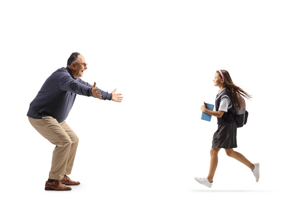 Full length profile shot of a schoolgirl running towards a mature man isolated on white background - Foto, Imagen
